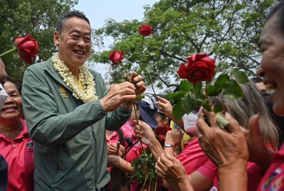 မတ် ၁၆ ရက်က ချင်းမိုင်မြို့ရှိ သီရိလန်နာ အမျိုးသားဥယျာဉ်ရှိ  ဝန်ထမ်းများထံမှ နှင်းဆီပန်းများလက်ခံနေသည့် ထိုင်းဝန်ကြီးချုပ်ဆရီထာ ထာဝီဆင်းကို တွေ့ရစဉ်(Photo:AFP)