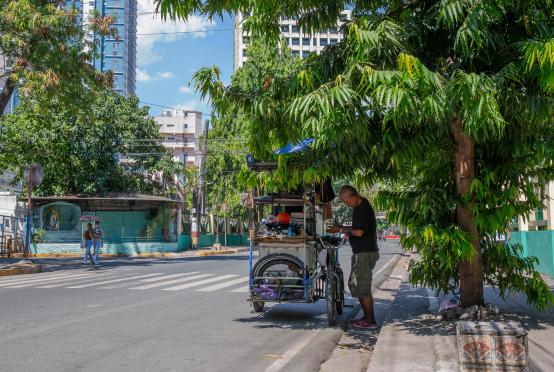 ဧပြီ ၂၈ ရက်က မလေးရှားနိုင်ငံ မနီလာမြို့တော်တွင် ပူပြင်းနေသည့် ရာသီဥတုအတွင်း သစ်ပင်တစ်ပင်အောက်တွင် အရိပ်ခိုနေသည့် လမ်းဘေးစျေးသည်တစ်ဦးကို တွေ့ရစဉ်